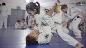 photo of two kids grappling in white gi's on blue mats